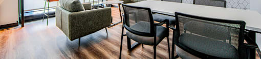 Shared workspace with a conference table, soft club chairs and bar-height counter with two stools looking out a large window at Vale Station Apartments in Waterloo, Ontario