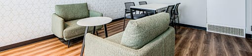 Shared workspace with soft club chairs, conference table with four chairs and a flat screen TV at Vale Station Apartments in Waterloo, ON