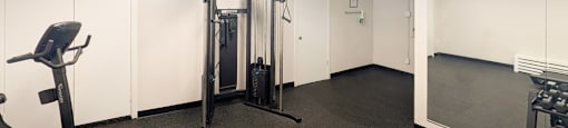 A gym room with a treadmill, a weight machine, and a squat rack.