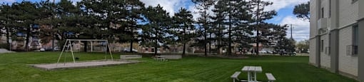 Green space with picnic tables and swing set at Village Tower Toronto ON