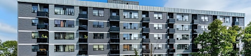A large grey apartment building with a parking lot in front.