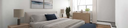 A bedroom with a large bed and a nightstand with a lamp.