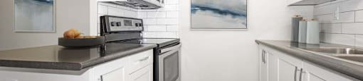 A kitchen with white cabinets and a black counter top.