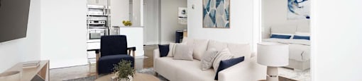 A modern living room with a white sofa, a coffee table, and a painting on the wall.