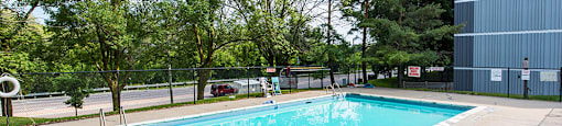 A small pool surrounded by a fence and trees.