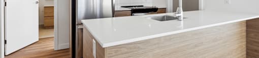 A modern kitchen with a white countertop and wooden cabinets.