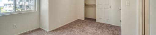 A room with a carpeted floor and a window overlooking a street.