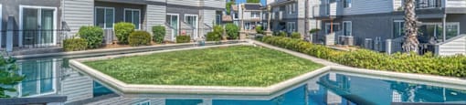 A pool surrounded by a fence and a grassy area in front of a building.