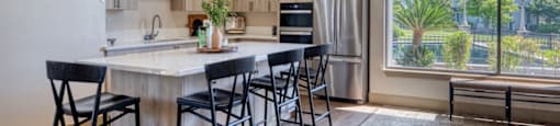 A kitchen with a table and chairs and a window overlooking a city.
