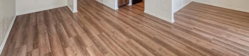 A spacious room with wooden flooring and a balcony with a railing.
