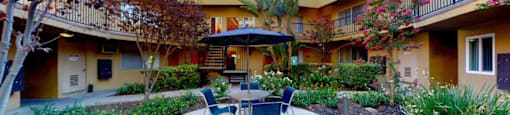 a patio with a table and chairs in a courtyard at The Marquee Apartments, North Hollywood, CA