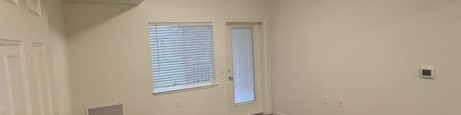 A room with a white door and a window with blinds.