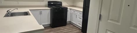 A kitchen with white cabinets and a black dishwasher.