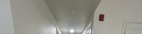 A long hallway with wood floors and white walls.