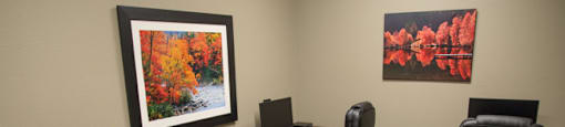 A room with a desk and chairs and a picture on the wall.