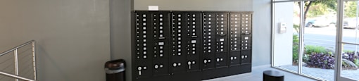 A hallway with a bench, a trash can, and a wall of lockers.
