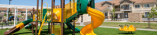A playground with a yellow and green slide.