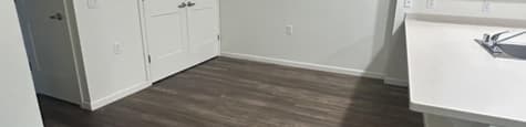A kitchen with white cabinets and a wooden floor.