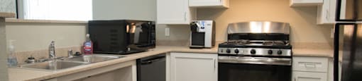 A kitchen with white cabinets and a black fridge.