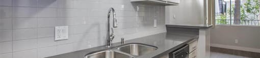 A modern kitchen with a stainless steel sink and white cabinets.