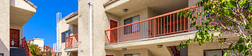 A building with a red railing and a tree in front.