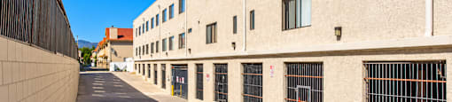 A long concrete walkway leads to a building with many windows.