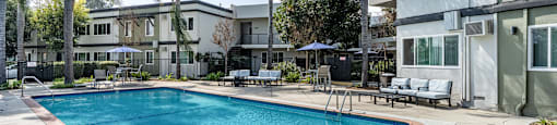 A swimming pool surrounded by palm trees and lounge chairs at The Marquee Apartments, California