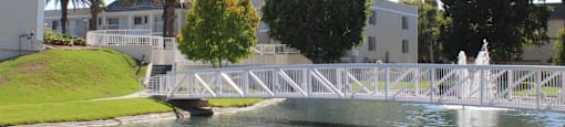 A white bridge over a body of water with a white fence and a white building in the background.