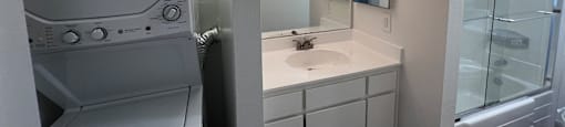 A white bathroom with a washer and dryer built in.