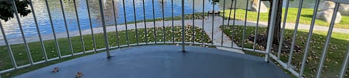 A balcony overlooks a body of water with a building in the background.