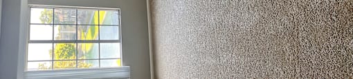 A room with a window and a wall covered in a textured material.