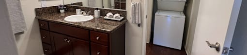 A bathroom with a brown vanity and a white rug.