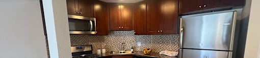 A kitchen with a refrigerator, microwave, and dishwasher.