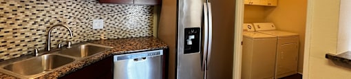 A kitchen with a refrigerator, sink, and cabinets.