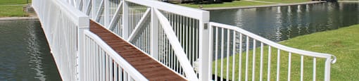A white railing over a body of water with buildings in the background.