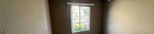 A room with a window and carpeted floor.