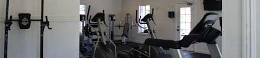 A gym with a variety of equipment including a treadmill, a stationary bike and a rowing machine.