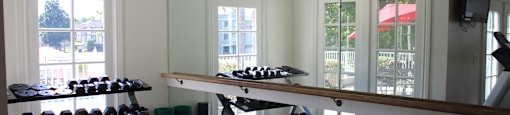 A gym with a row of dumbbells on the left and a row of treadmills on the right.