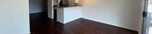 A room with wooden floors and a kitchenette.