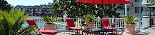 A red umbrella is in front of a table and chairs.