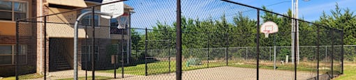 Basketball court is enclosed by a black fence.