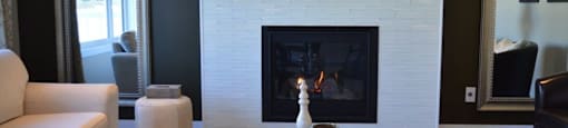 A living room with a fireplace and a glass coffee table.