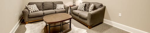 A living room with a grey couch and a brown coffee table.