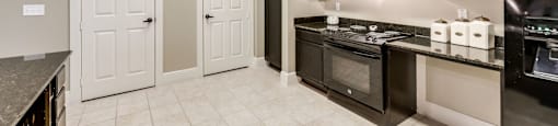 A kitchen with black cabinets and a white tile floor.