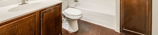 A white bathroom with a toilet, sink, and a wooden door.