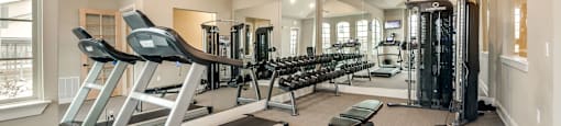 A spacious home gym with treadmills, elliptical machines, and weightlifting equipment.