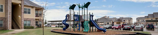 Playground with a slide and swings in a grassy area.