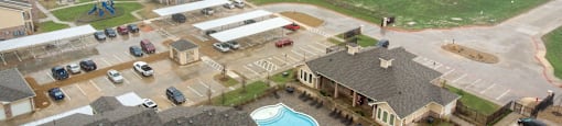 Bird's eye view of a residential area with houses, cars, and a swimming pool.