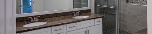 A bathroom with a sink, mirror, and shower.