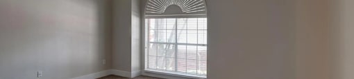 A room with a carpeted floor and a window with blinds.